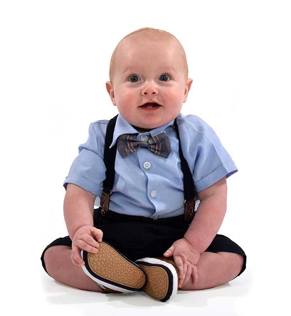 Archer- child under 1 sat up in his shirt and suspenders outfit in the studio white background 