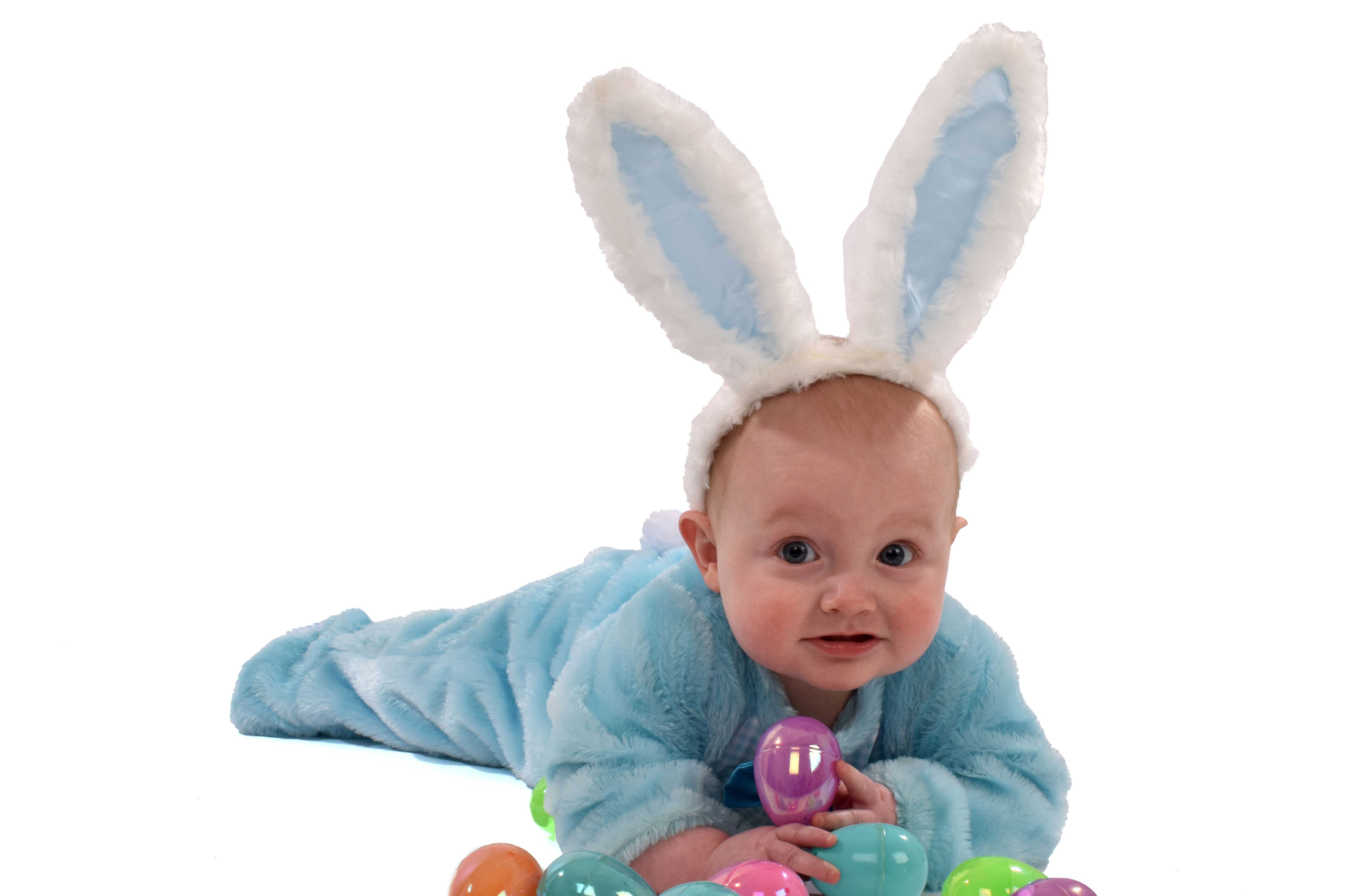 baby Archer under 1 dressed as a Bunny for easter theme with some coloured plastic eggs white background