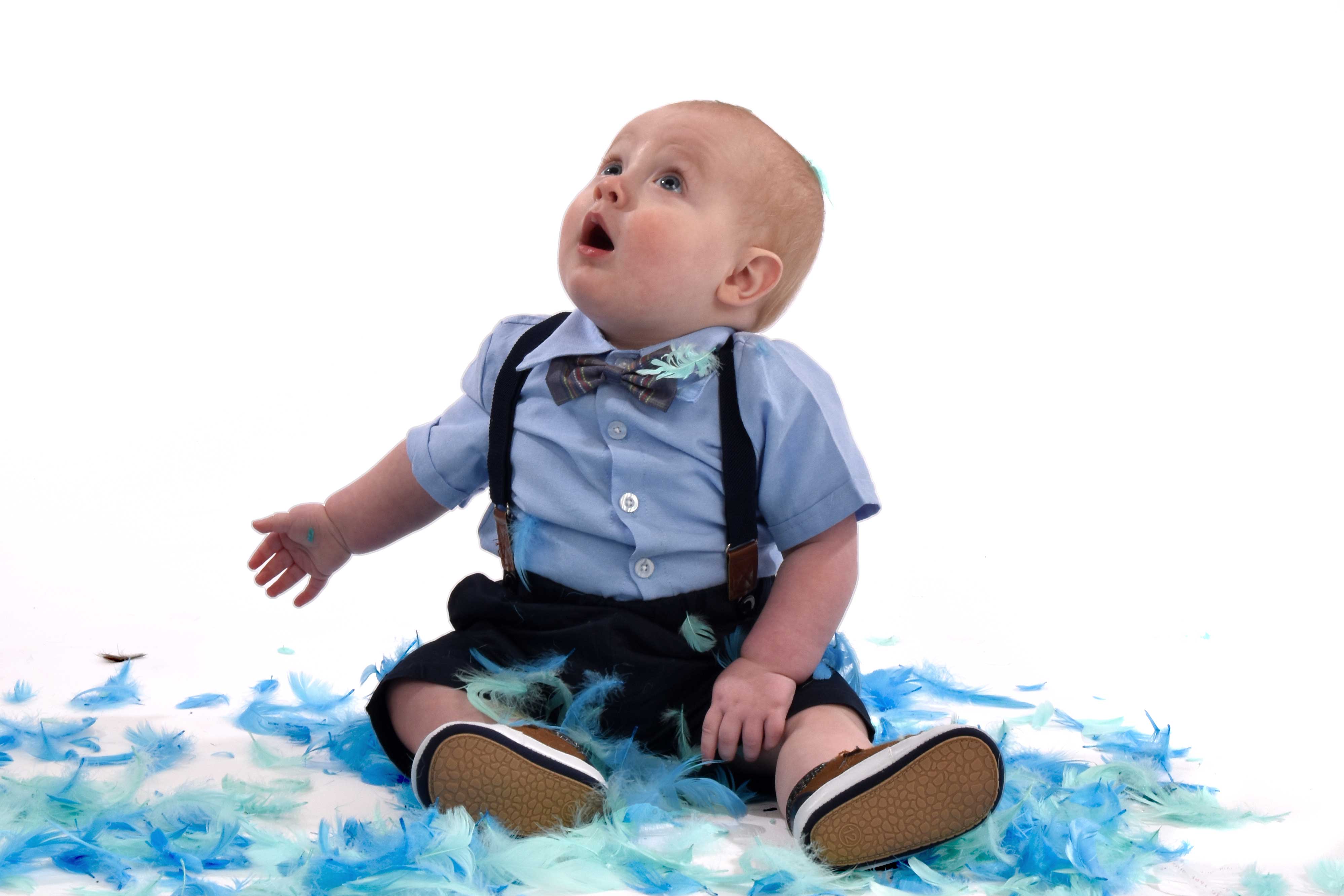Archer under 1 in fancy dress sitting in blue feathers looking up 