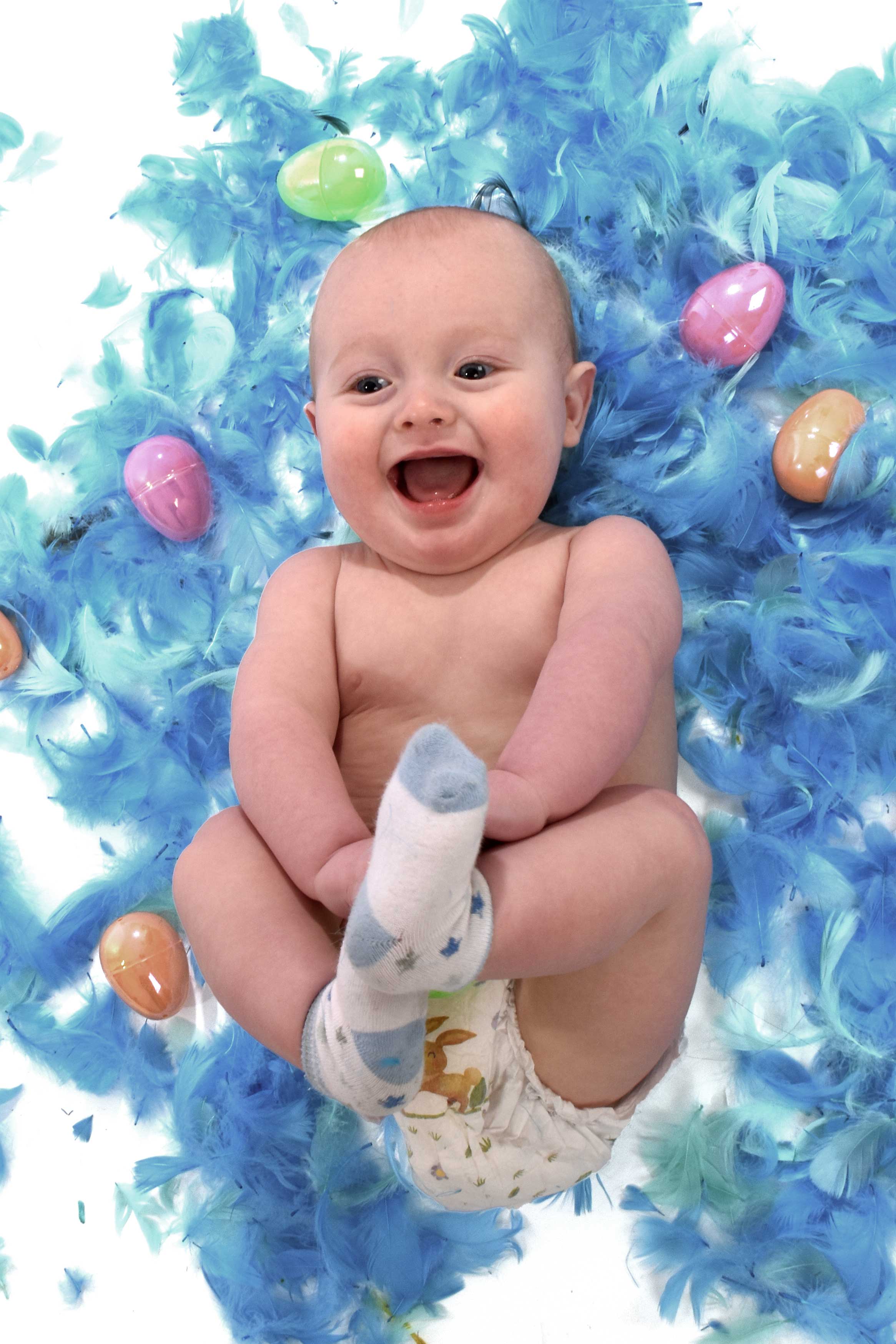 baby archer under 1 lying in blue feathers white background