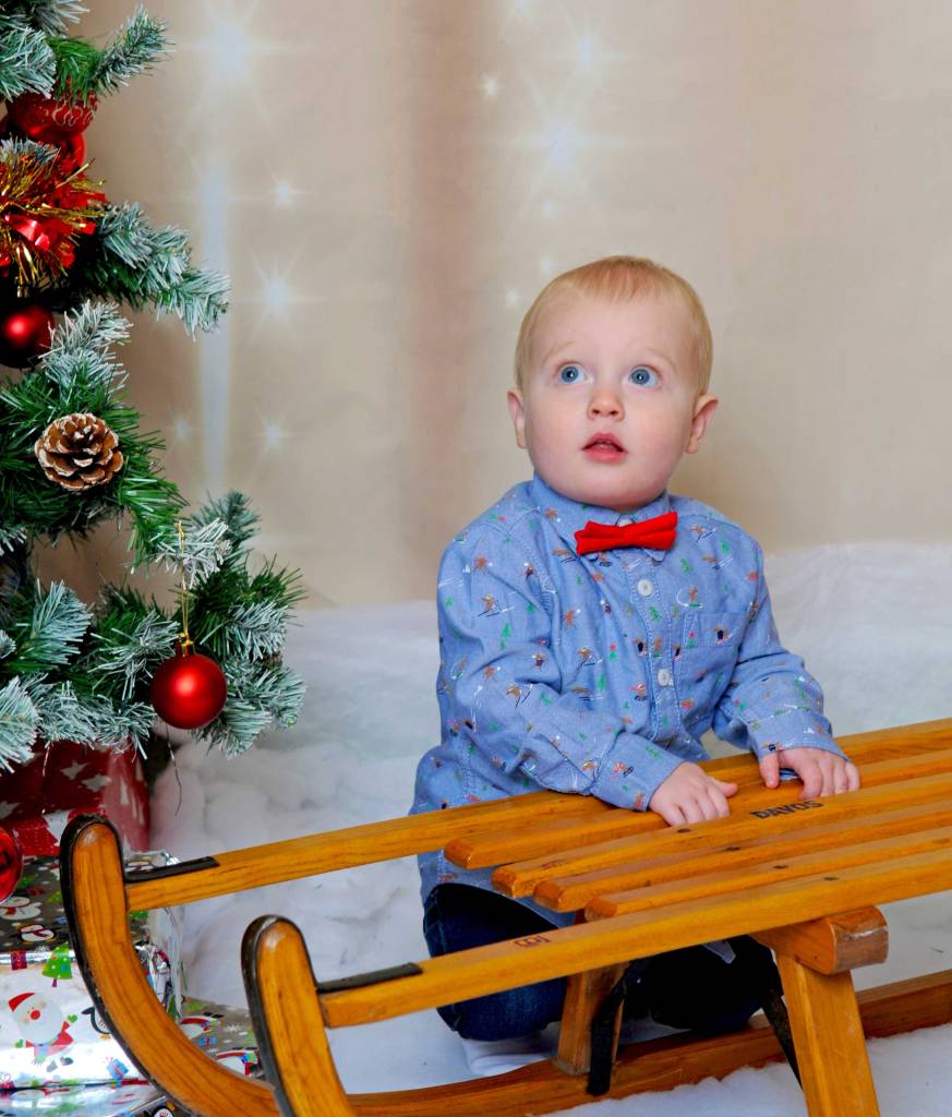 Child looking up in awe next to a christmas tree 